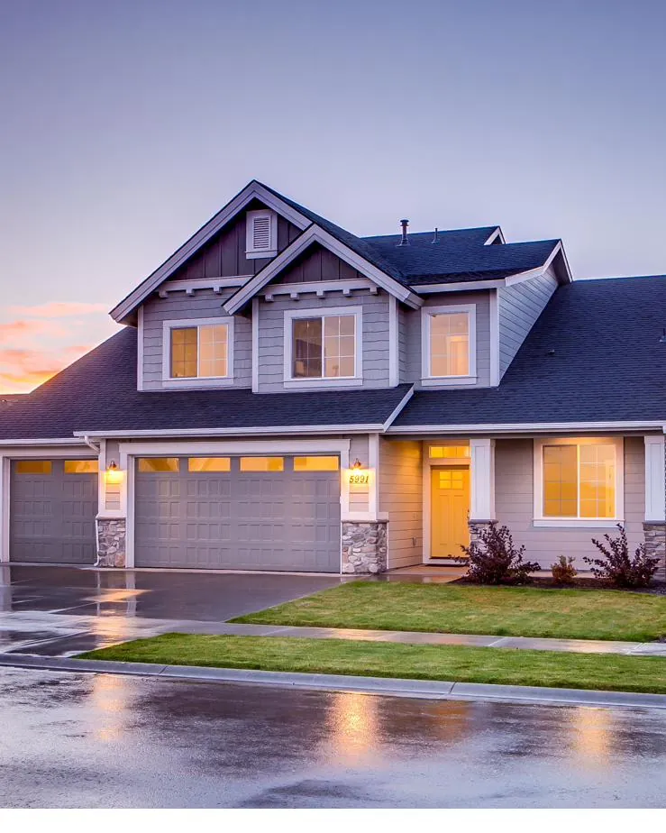 A two-storey residential home at dusk with warmly lit windows